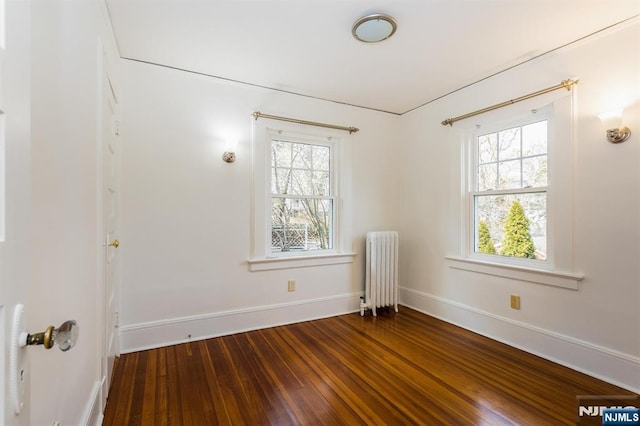 unfurnished room with hardwood / wood-style floors, radiator heating unit, and baseboards