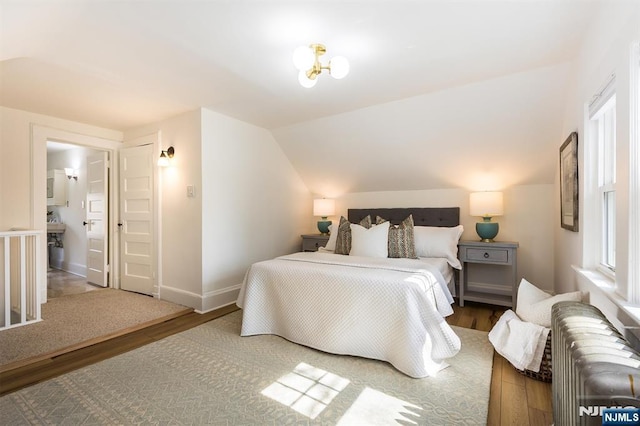 bedroom with vaulted ceiling, radiator heating unit, wood finished floors, and baseboards