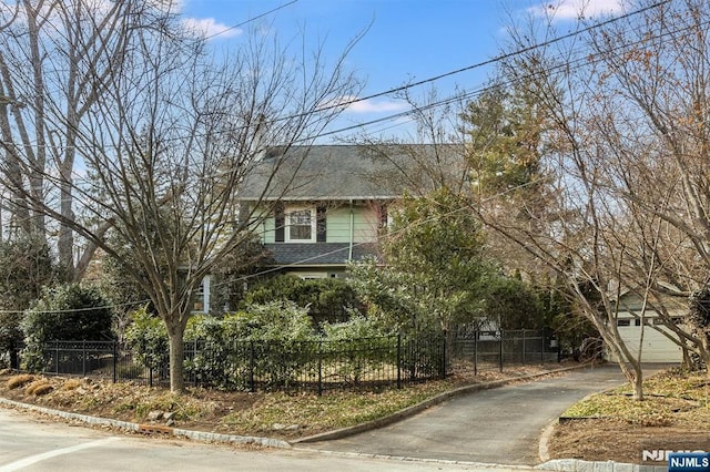 view of front of home with a fenced front yard and roof with shingles