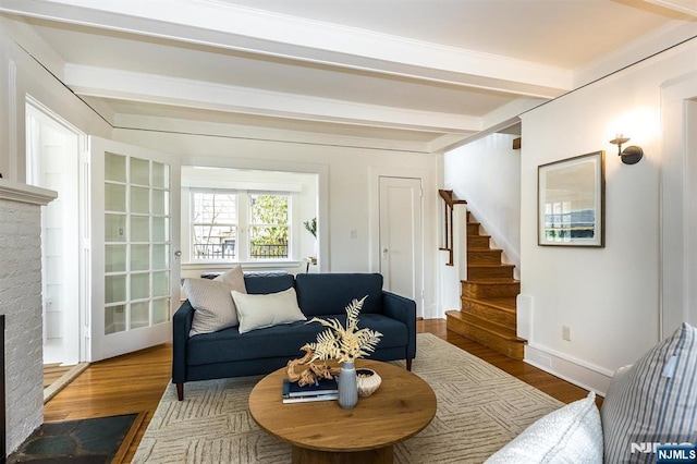 living room featuring stairway, beamed ceiling, wood finished floors, and a fireplace