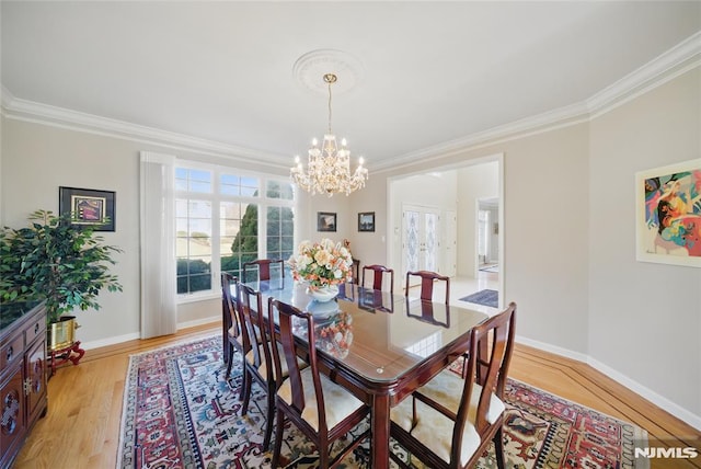 dining room with baseboards, an inviting chandelier, crown molding, and light wood finished floors