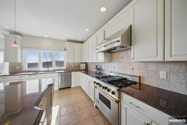 kitchen featuring a sink, backsplash, stainless steel appliances, wall chimney exhaust hood, and light tile patterned floors