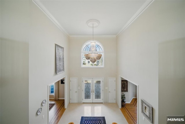 foyer entrance with crown molding, a high ceiling, wood finished floors, and french doors