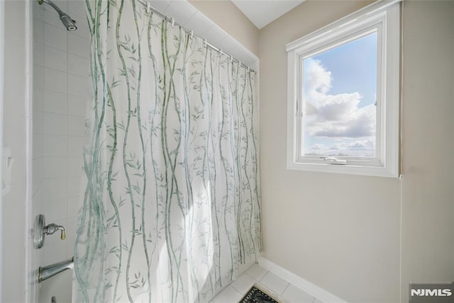 full bathroom featuring tile patterned floors, baseboards, and shower / bath combo