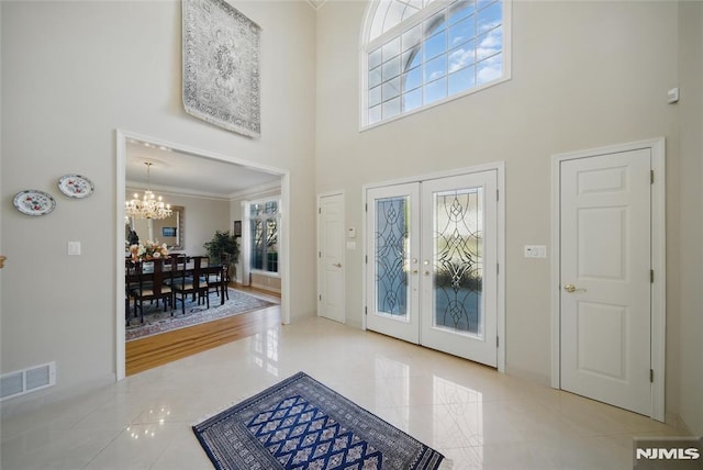 foyer entrance featuring a chandelier, visible vents, french doors, and a towering ceiling