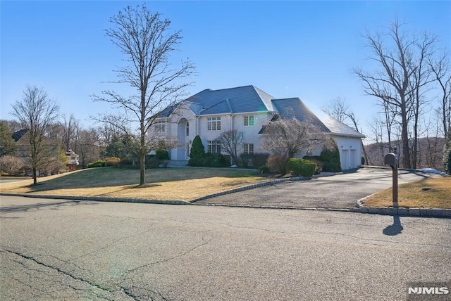 french country home featuring aphalt driveway and a front yard