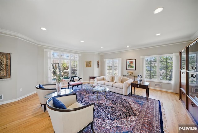 living area featuring visible vents, light wood-type flooring, and crown molding