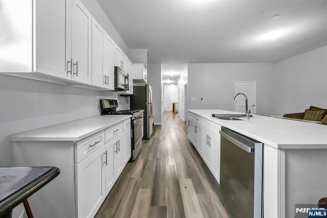 kitchen featuring appliances with stainless steel finishes, white cabinetry, light countertops, and a sink