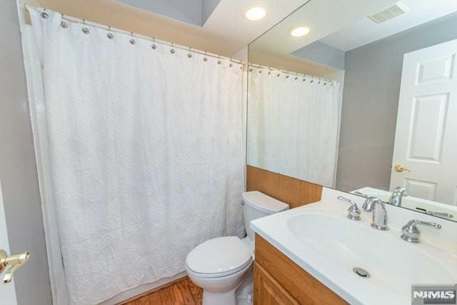 full bath with vanity, wood finished floors, visible vents, curtained shower, and toilet