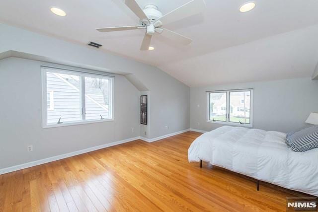 bedroom featuring lofted ceiling, light wood-style flooring, multiple windows, and baseboards