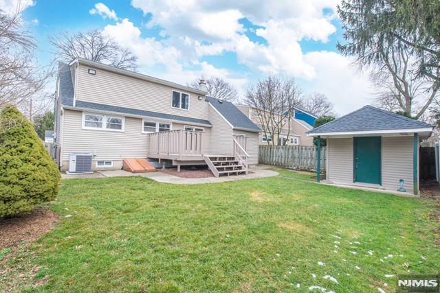 rear view of house with central air condition unit, a lawn, fence, an outdoor structure, and a wooden deck