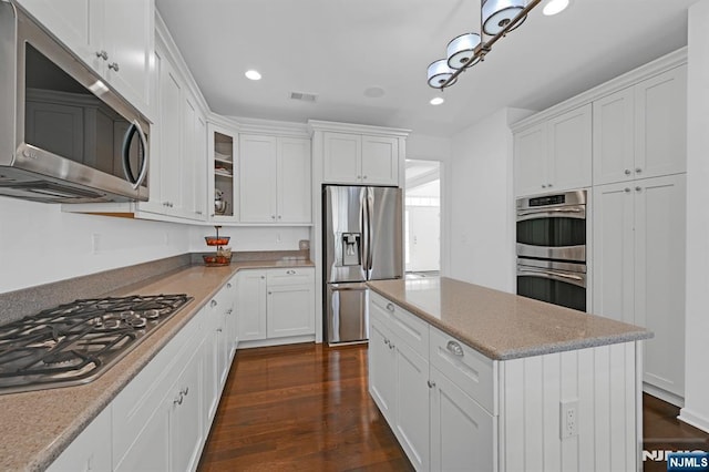 kitchen with white cabinets, dark wood-style floors, visible vents, and stainless steel appliances