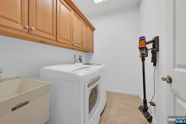 washroom featuring light tile patterned floors, baseboards, cabinet space, a sink, and washer and clothes dryer