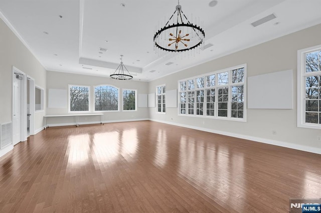 unfurnished living room featuring a notable chandelier, a raised ceiling, visible vents, and hardwood / wood-style floors