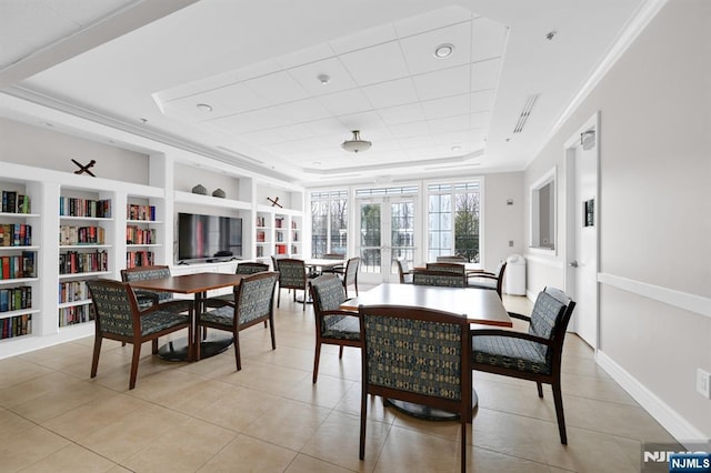 dining area featuring french doors, a raised ceiling, ornamental molding, and light tile patterned flooring