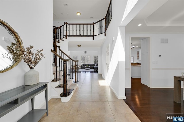 entrance foyer featuring visible vents, baseboards, crown molding, and stairway