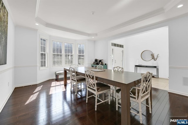 dining room featuring visible vents, crown molding, baseboards, hardwood / wood-style flooring, and a raised ceiling