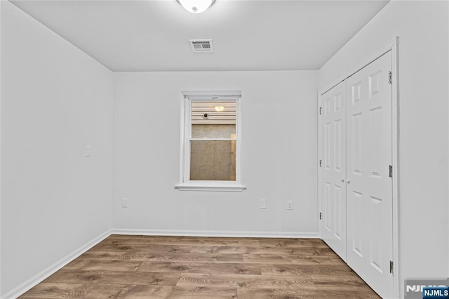 unfurnished bedroom with visible vents, baseboards, and wood finished floors