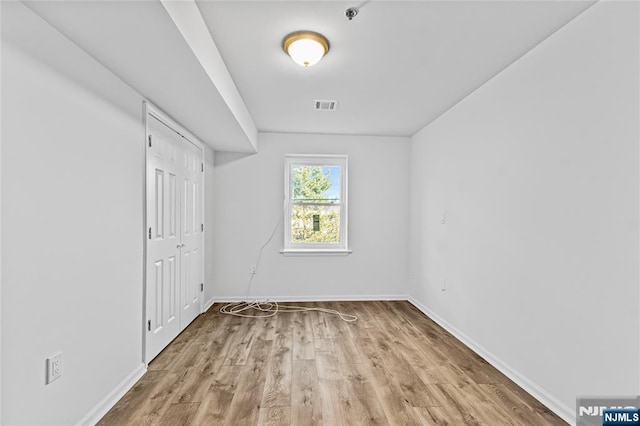 unfurnished room featuring visible vents, baseboards, and wood finished floors