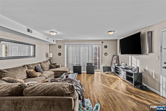 living area with visible vents, baseboards, and wood finished floors