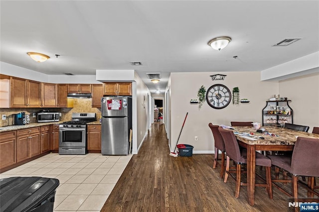 kitchen featuring brown cabinetry, visible vents, and appliances with stainless steel finishes