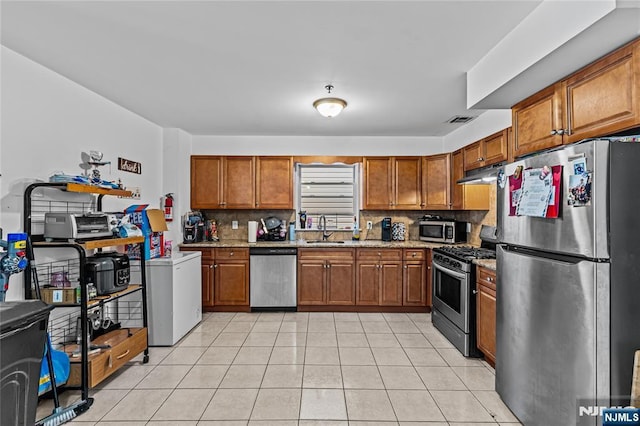 kitchen with a sink, stainless steel appliances, brown cabinets, and visible vents