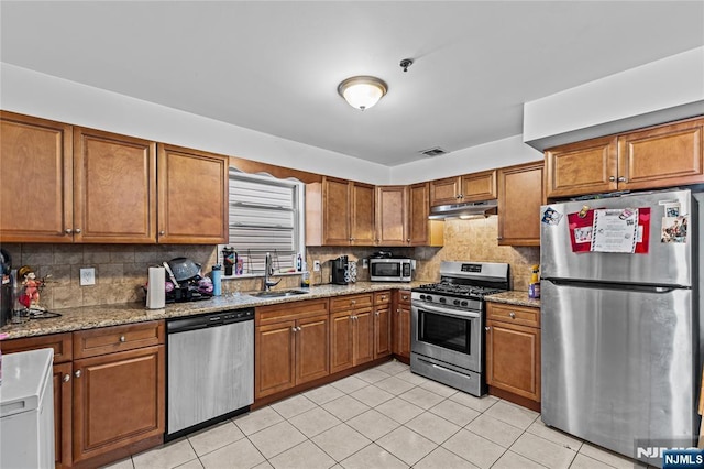 kitchen featuring brown cabinets, appliances with stainless steel finishes, and a sink