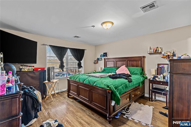 bedroom featuring visible vents, baseboards, and wood finished floors