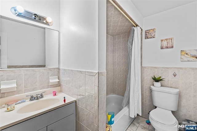 full bath featuring vanity, a wainscoted wall, shower / bath combo, tile walls, and toilet