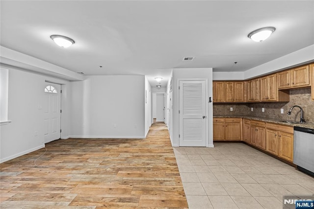 kitchen featuring visible vents, a sink, light wood-style floors, stainless steel dishwasher, and backsplash