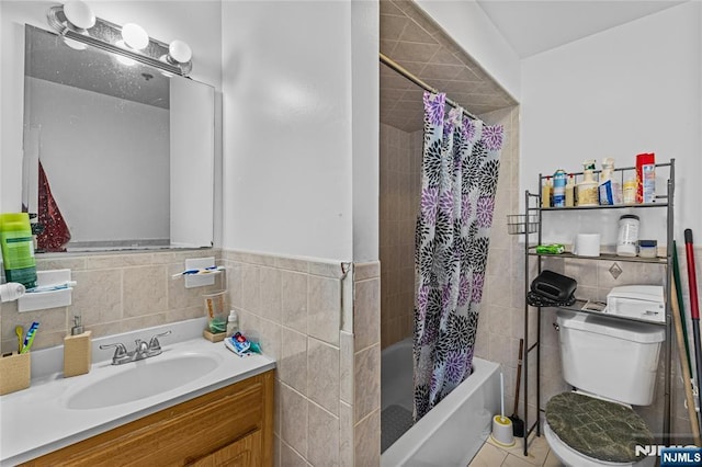 bathroom with tile walls, toilet, shower / tub combo with curtain, wainscoting, and vanity