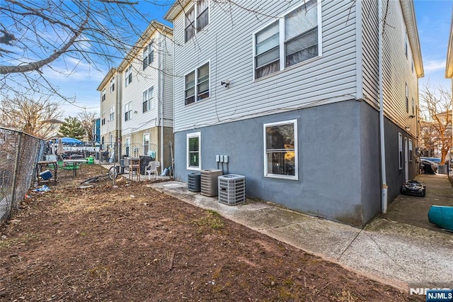 back of property featuring central air condition unit, stucco siding, and fence