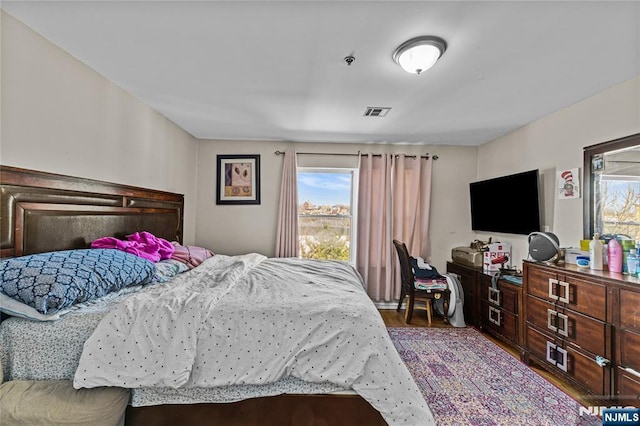 bedroom with visible vents, multiple windows, and wood finished floors