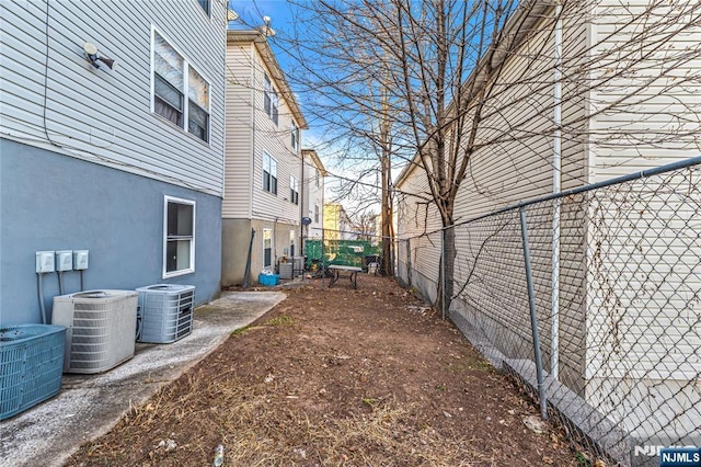 view of yard with central air condition unit and fence