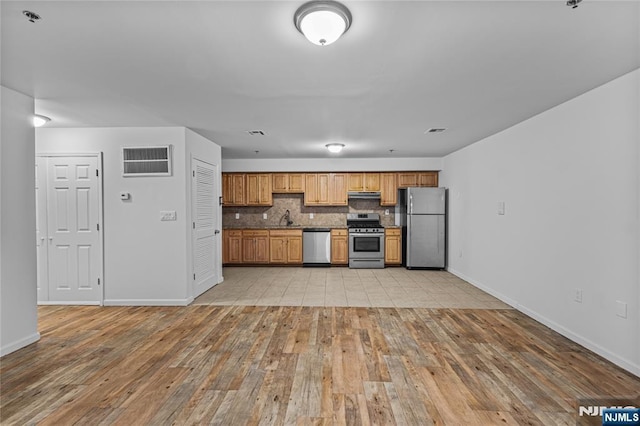 kitchen with visible vents, light wood-style flooring, under cabinet range hood, tasteful backsplash, and stainless steel appliances