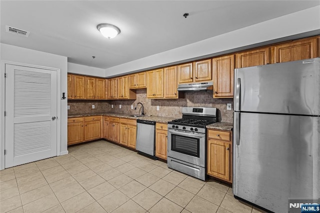 kitchen featuring visible vents, under cabinet range hood, a sink, backsplash, and appliances with stainless steel finishes