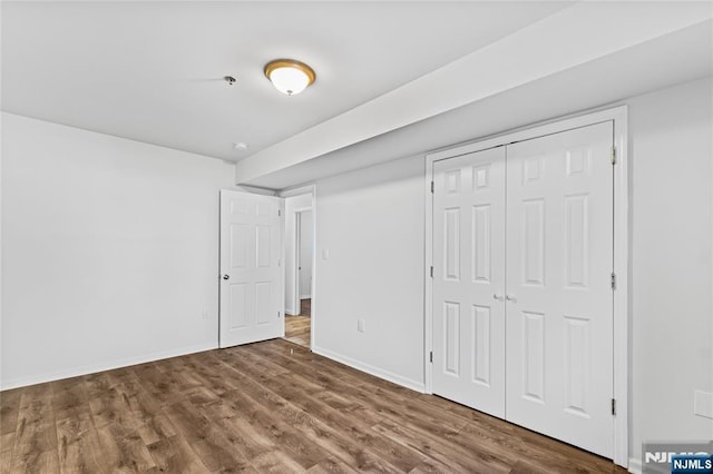 unfurnished bedroom with a closet, baseboards, and wood finished floors