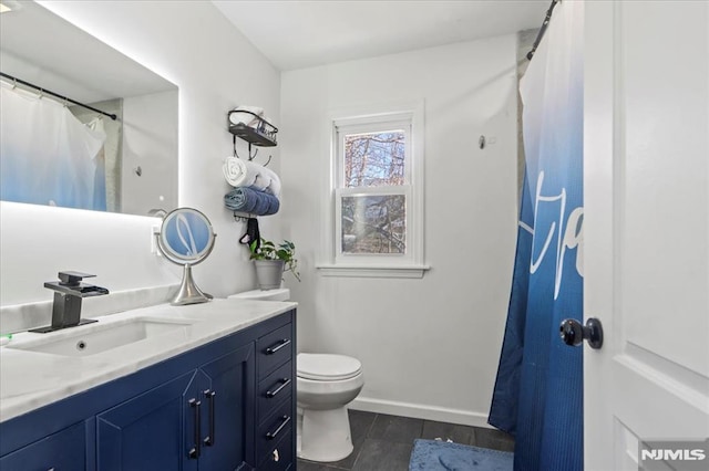 full bathroom featuring toilet, vanity, and baseboards