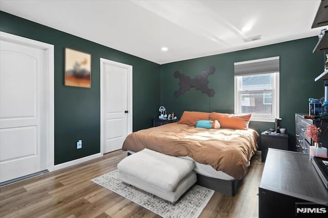 bedroom featuring visible vents, baseboards, and wood finished floors