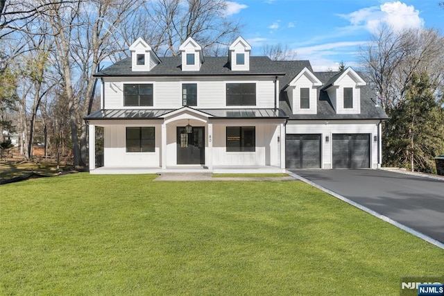 view of front of home with a porch, driveway, a front yard, and a standing seam roof