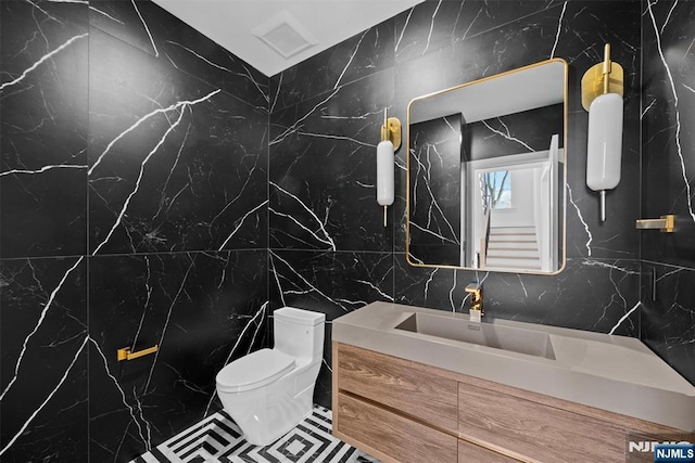 bathroom featuring vanity, tile walls, and toilet