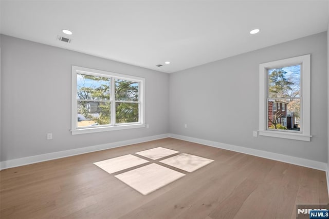 empty room featuring visible vents, a healthy amount of sunlight, and baseboards