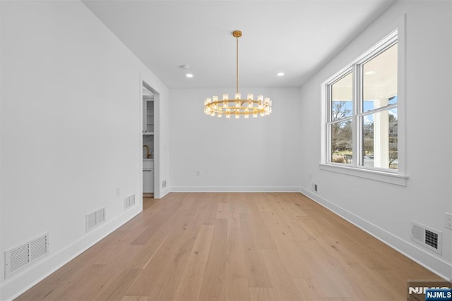 unfurnished dining area featuring light wood finished floors, visible vents, baseboards, and a notable chandelier