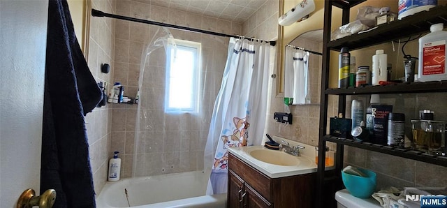 full bath with tile walls, toilet, vanity, and shower / bath combo