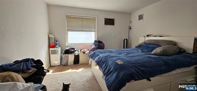 bedroom featuring carpet, visible vents, and a wall mounted air conditioner