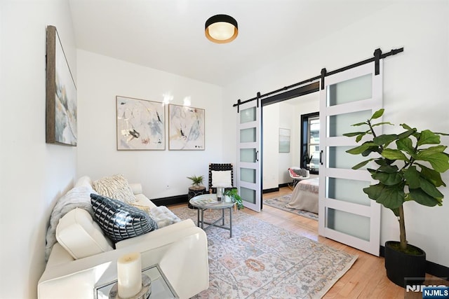 living area with a barn door, wood finished floors, and baseboards