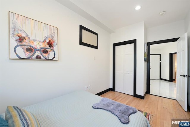 bedroom featuring recessed lighting, a closet, light wood finished floors, and baseboards