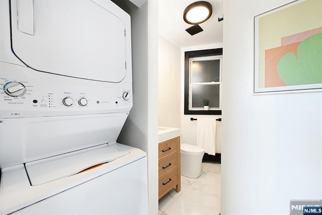 washroom featuring laundry area, marble finish floor, and stacked washer and clothes dryer