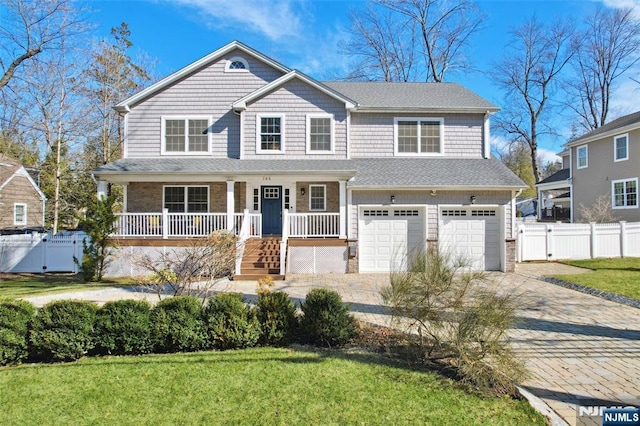 view of front of home with a front lawn, decorative driveway, covered porch, and an attached garage