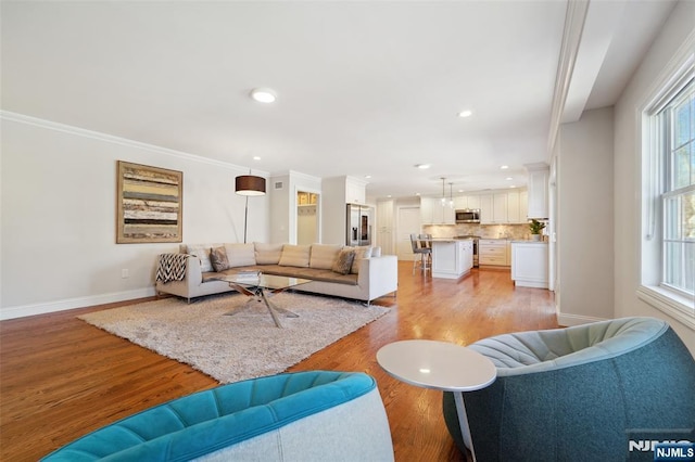 living room featuring recessed lighting, baseboards, light wood-style flooring, and ornamental molding